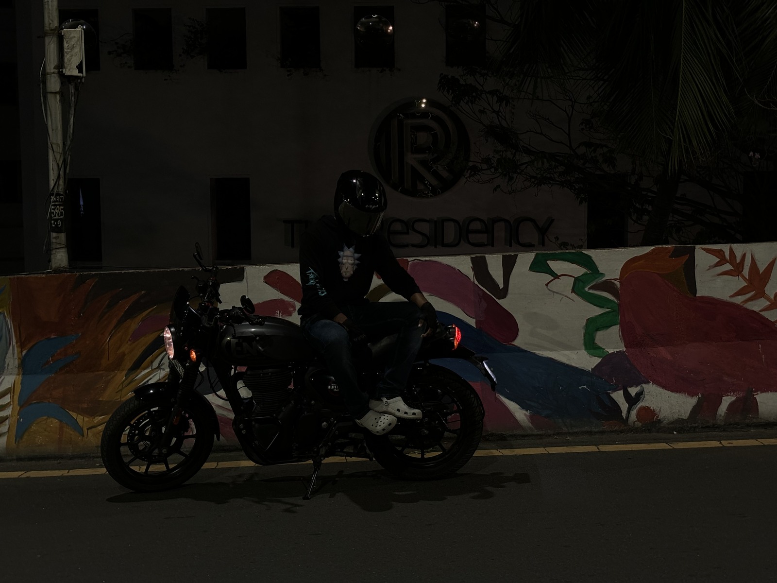 A helmeted rider on a motorcycle at night